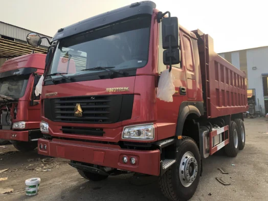 Red SINOTRUK dump truck in a vehicle yard at sunset.
