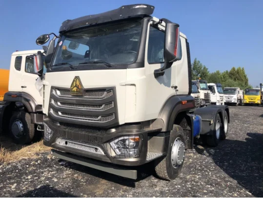 White Sinotruk HOWO tractor truck in a vehicle yard under a clear blue sky.