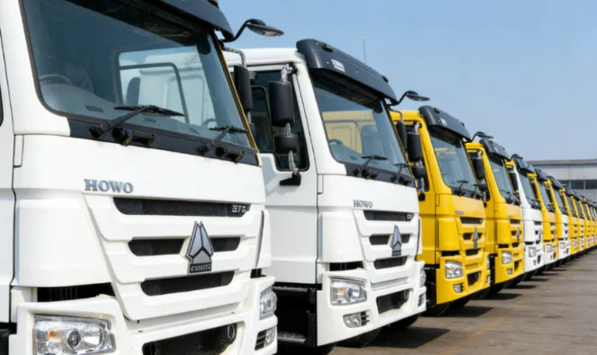 Row of white and yellow HOWO concrete mixer trucks in inventory.