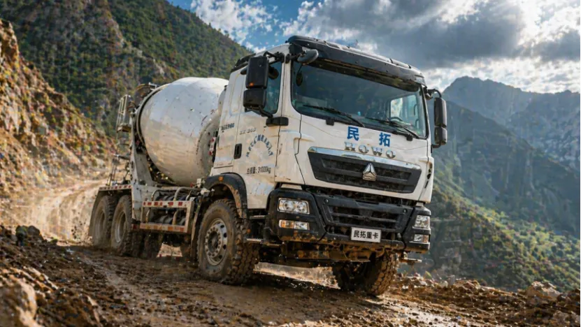 Sinotruk HOWO concrete mixer truck driving on a muddy mountain road