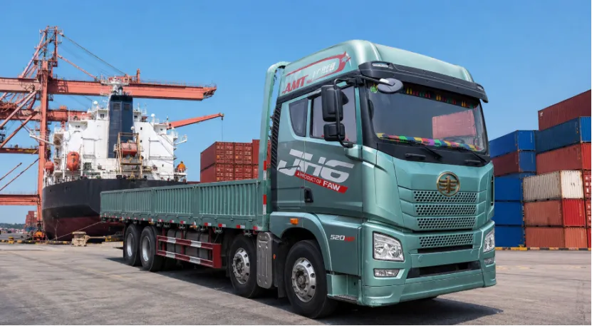 Green FAW flatbed truck parked at a cargo shipping port