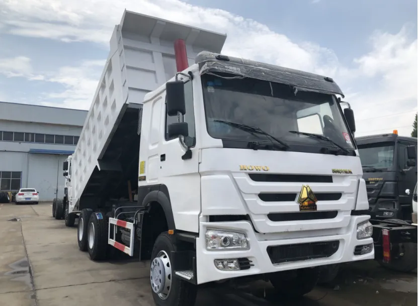 White HOWO dump truck with its bed raised, parked in an industrial lot