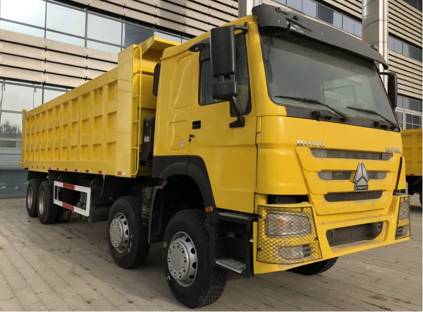 Front and side view of a yellow HOWO dump truck parked outdoors